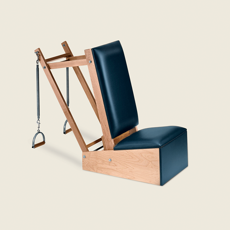 Pilates arm chair with wood frame, black padding, and attached springs for resistance-based workouts.